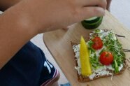 Brot mit Tomaten, Paprika und Kresse, darüber Hand