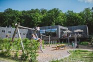 Spielplatz mit Kindern vor Holzgebäude