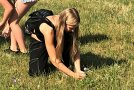 Schülerin bei der Insektensuche hockend im Gras